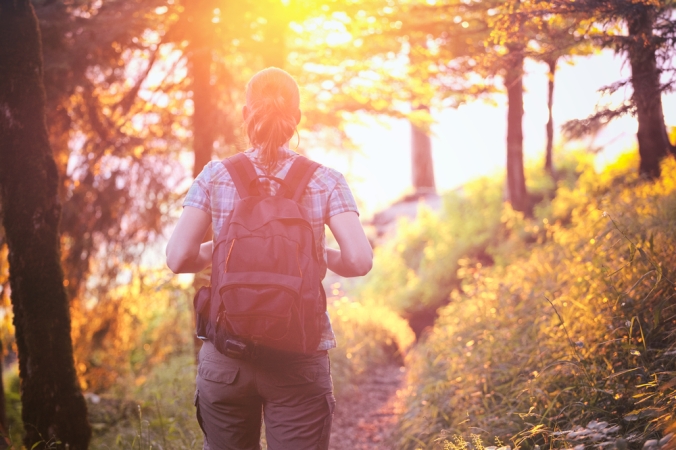A woman with a rucksack enjoying a walk outdoors in a forest